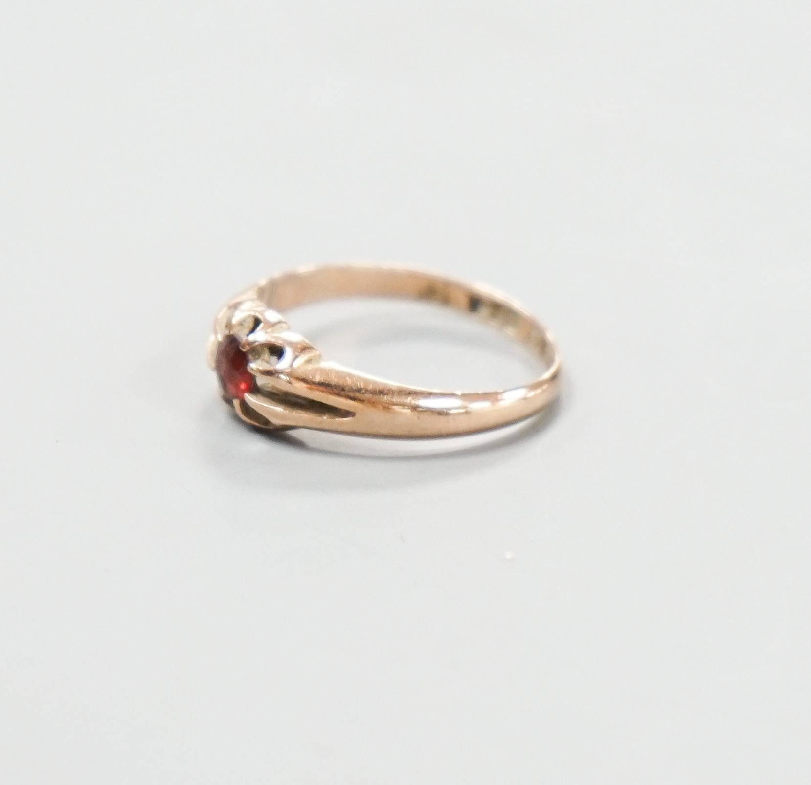 An Edwardian 9ct gold and claw set garnet ring, size N, gross 2.2 grams.